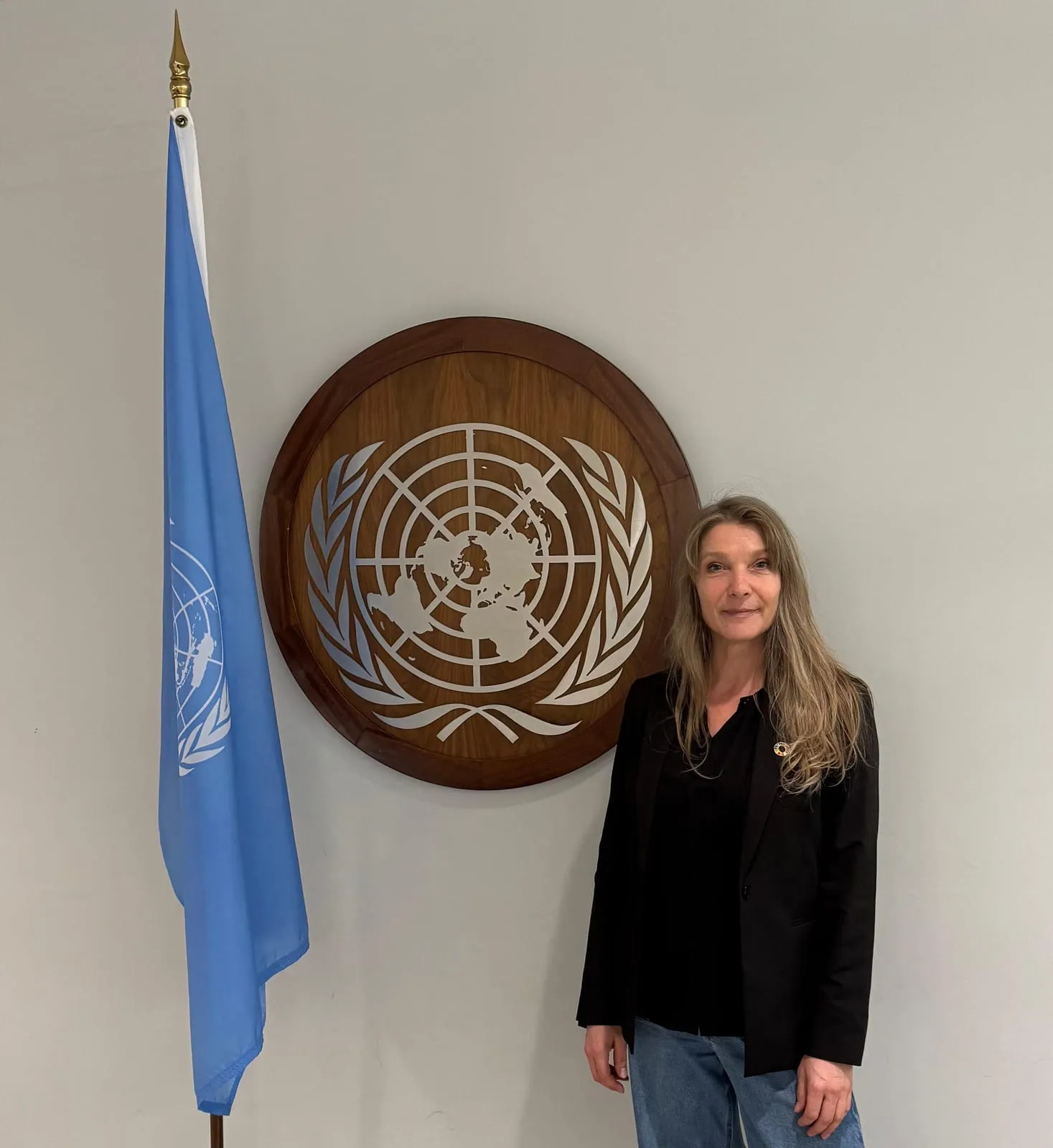 Maria Stern neben Flagge und Emblem der Vereinten Nationen