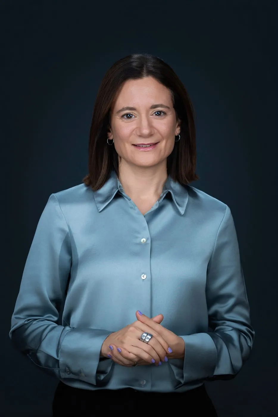 Sonja Aziz in hellblauer Bluse vor dunkelblauem Hintergrund