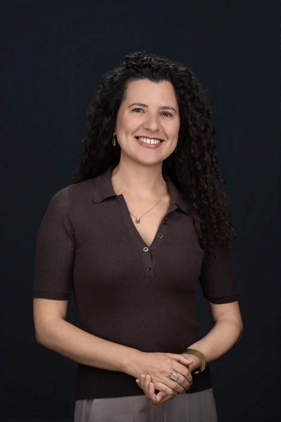 Anna Marynenko mit dunklen Locken in braunem Strickshirt vor dunkelblauem Hintergrund