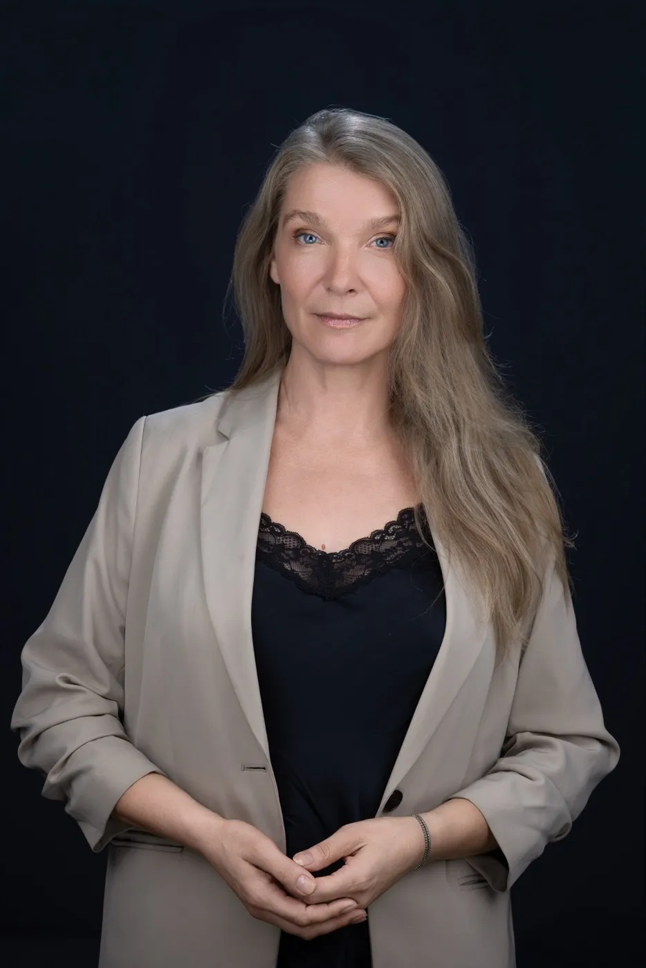 Maria Stern in beigem Sakko und schwarzem Spitzentop vor dunkelblauem Hintergrund
