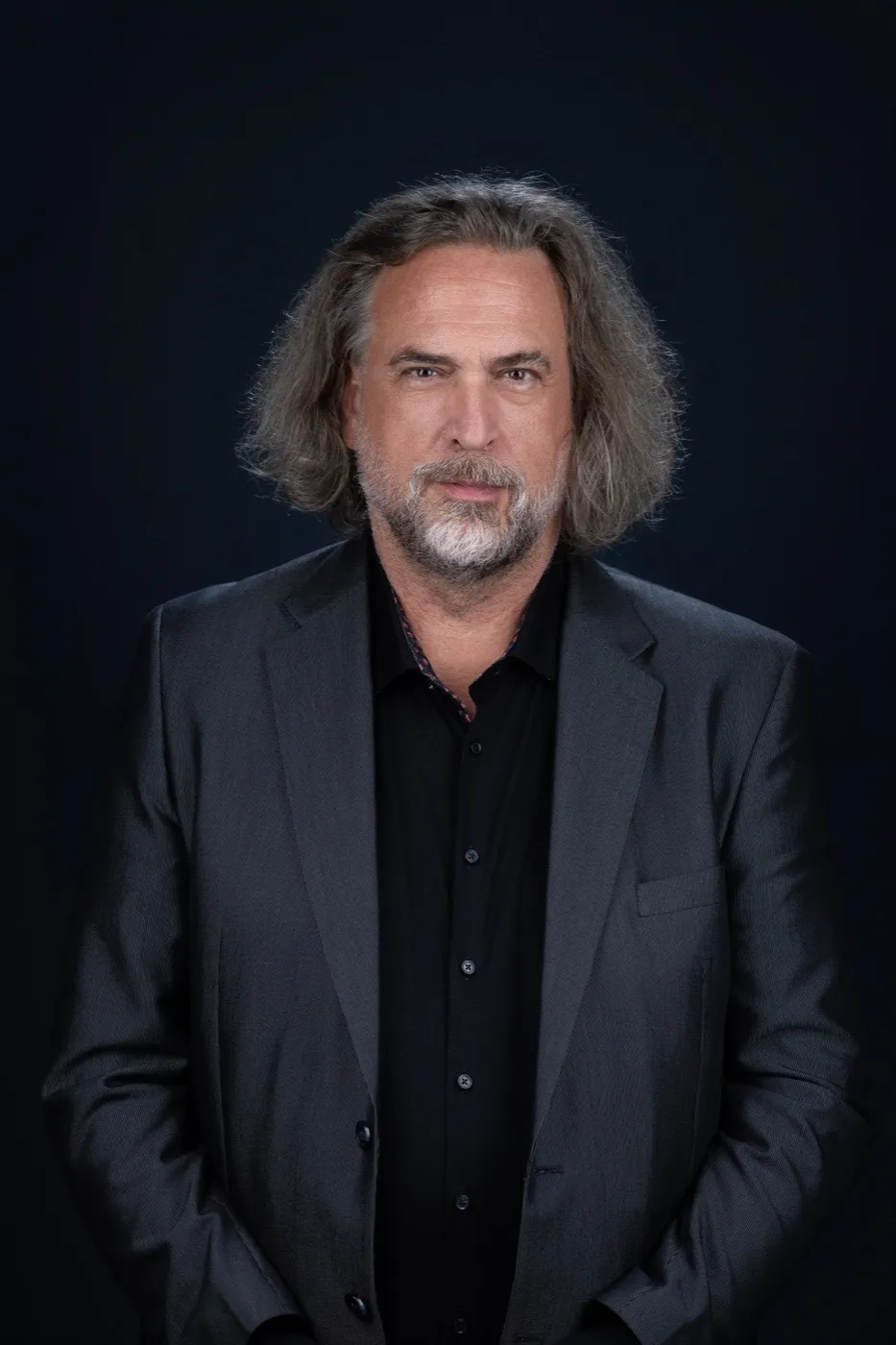 Walter Wratschko in grauem Sakko und schwarzem Hemd vor dunkelblauem Hintergrund