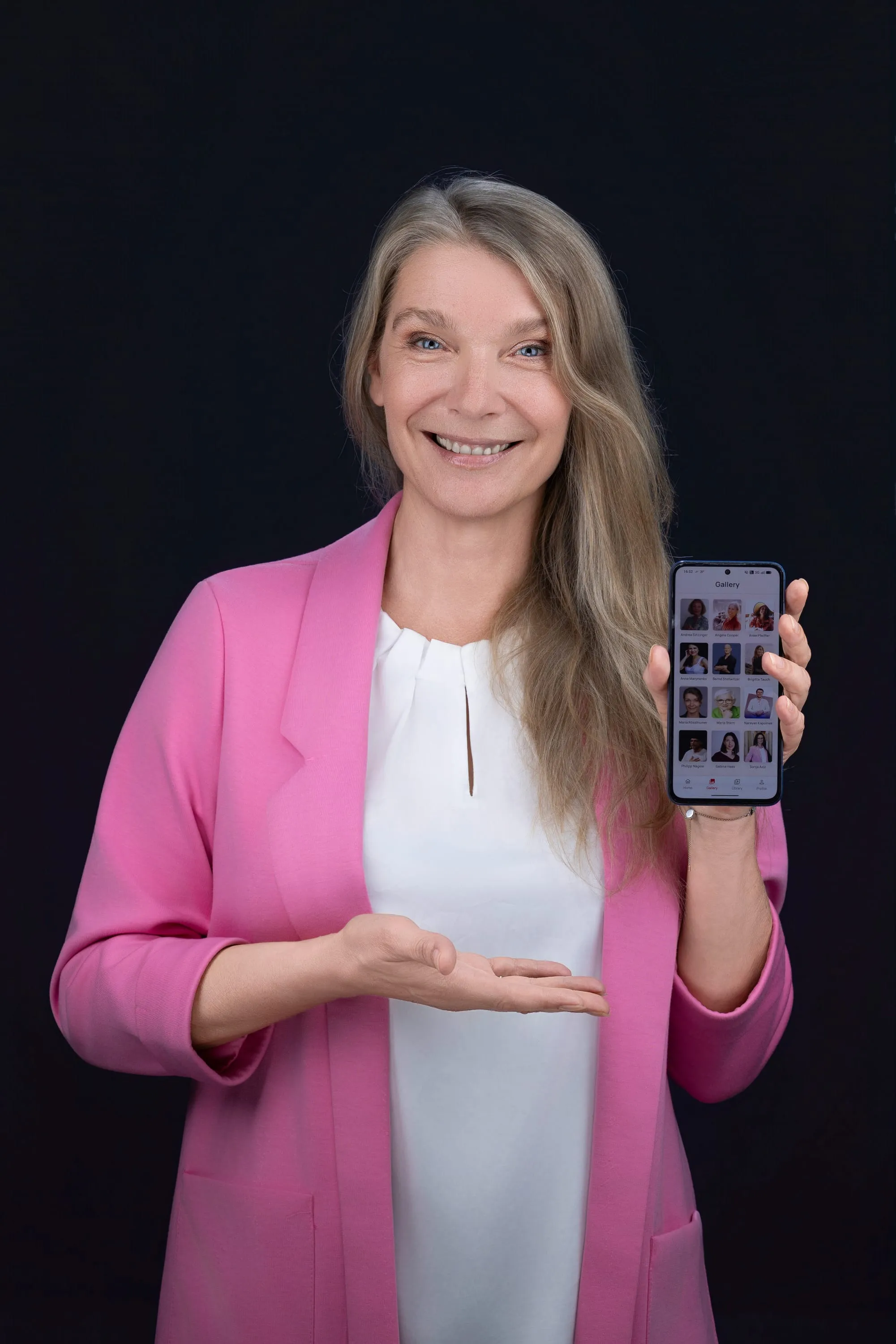 Maria Stern im pinken Blazer zeigt lächelnd die THANKS App auf ihrem Smartphone